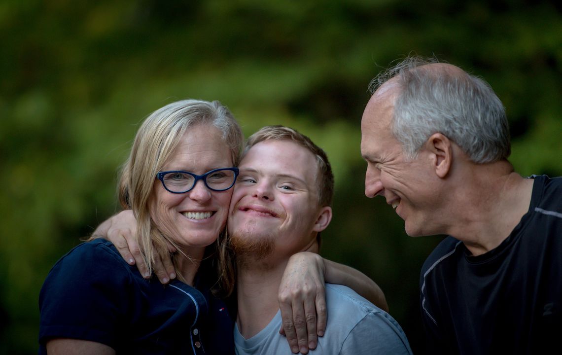 A mother and father hug their son, who has Down's syndrome.