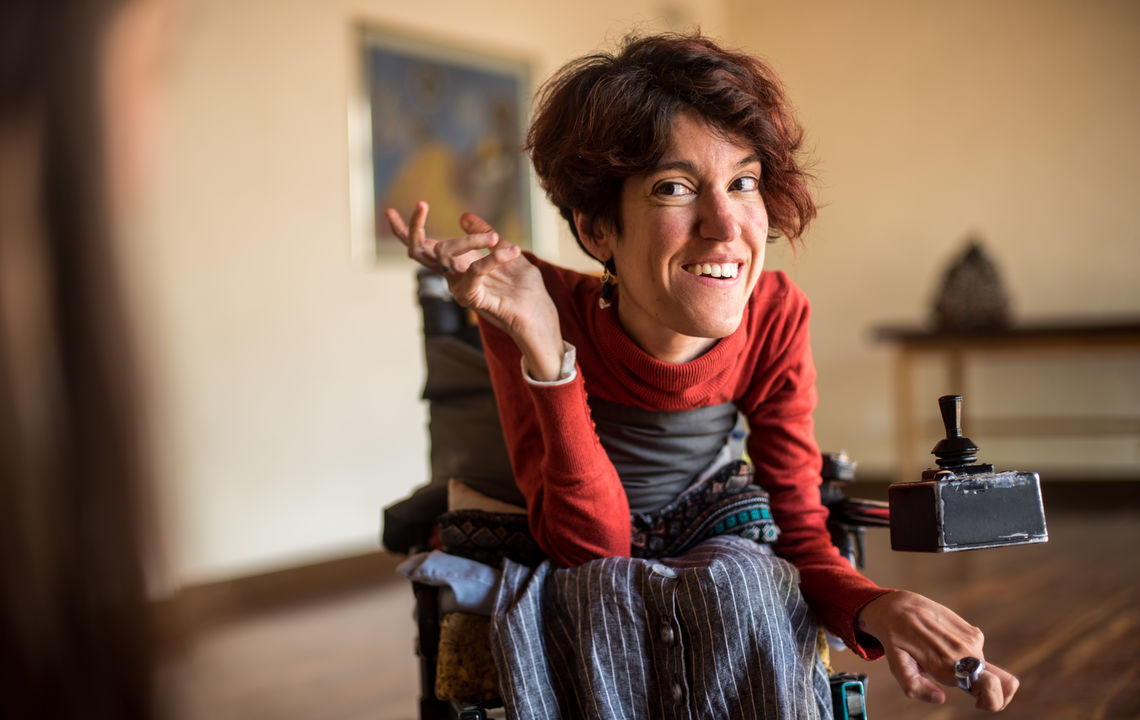 A woman in a wheelchair looks at the camera