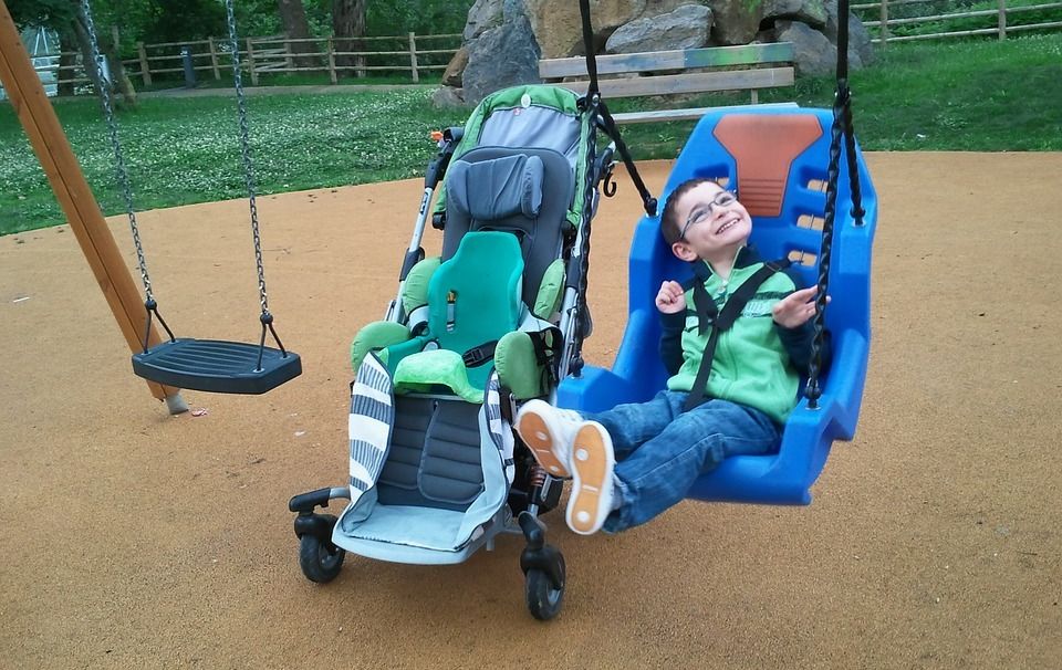 A child rides in an adapted swing on a playground