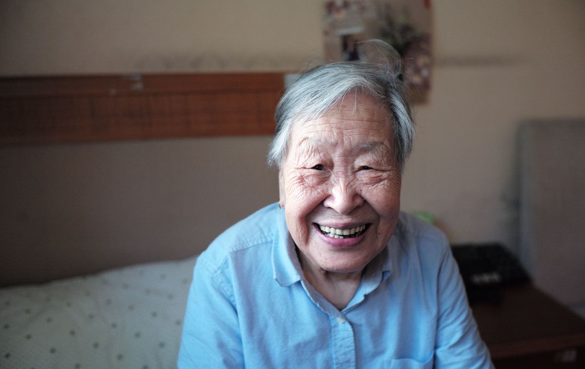 senior woman smiling and sitting on bed.