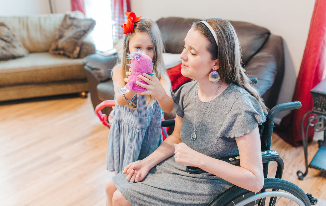 A mother in a wheelchair plays with her daughter.