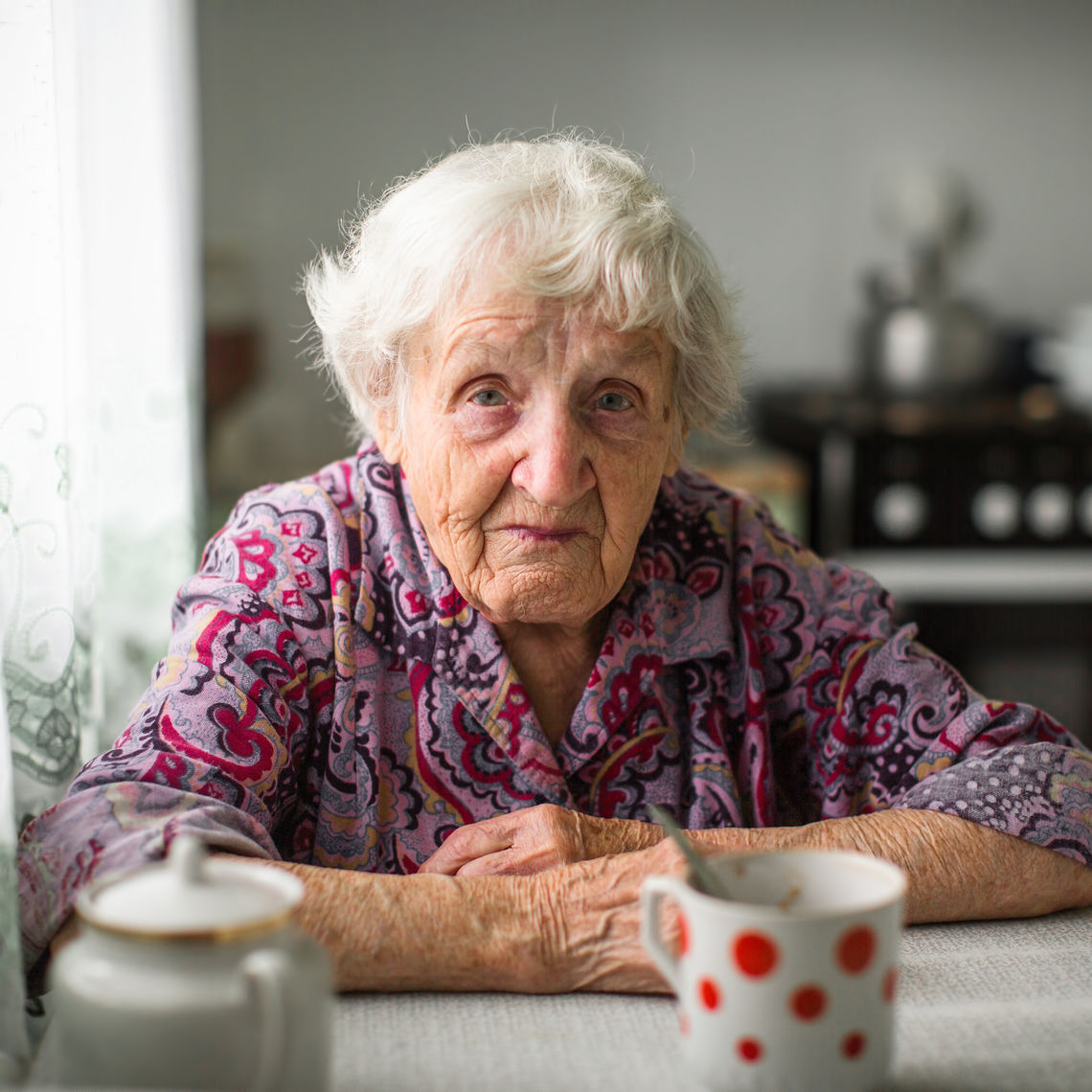 An elderly woman sitting at the kitchen table.