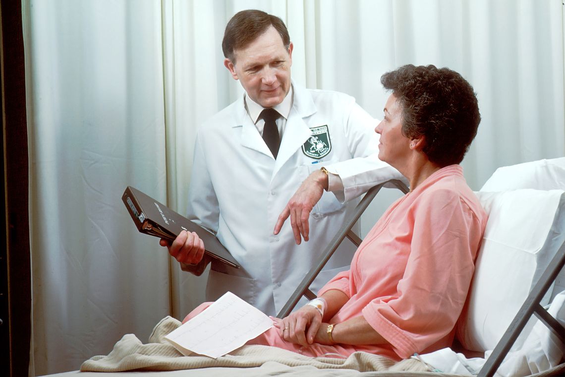 A doctor talks to a woman in a hospital bed.