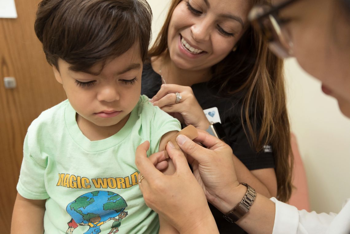 A doctor puts a bandaid on a boy's arm after giving him a shot.