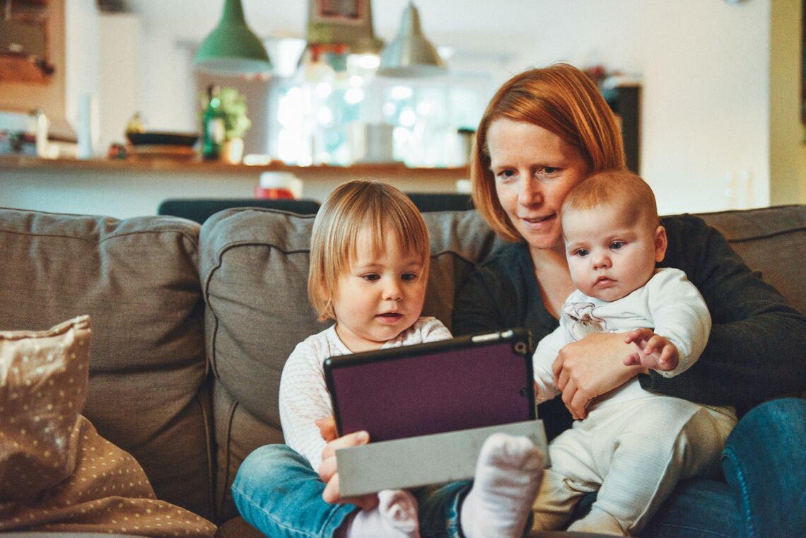 A mother looks at something on an iPad with her two children