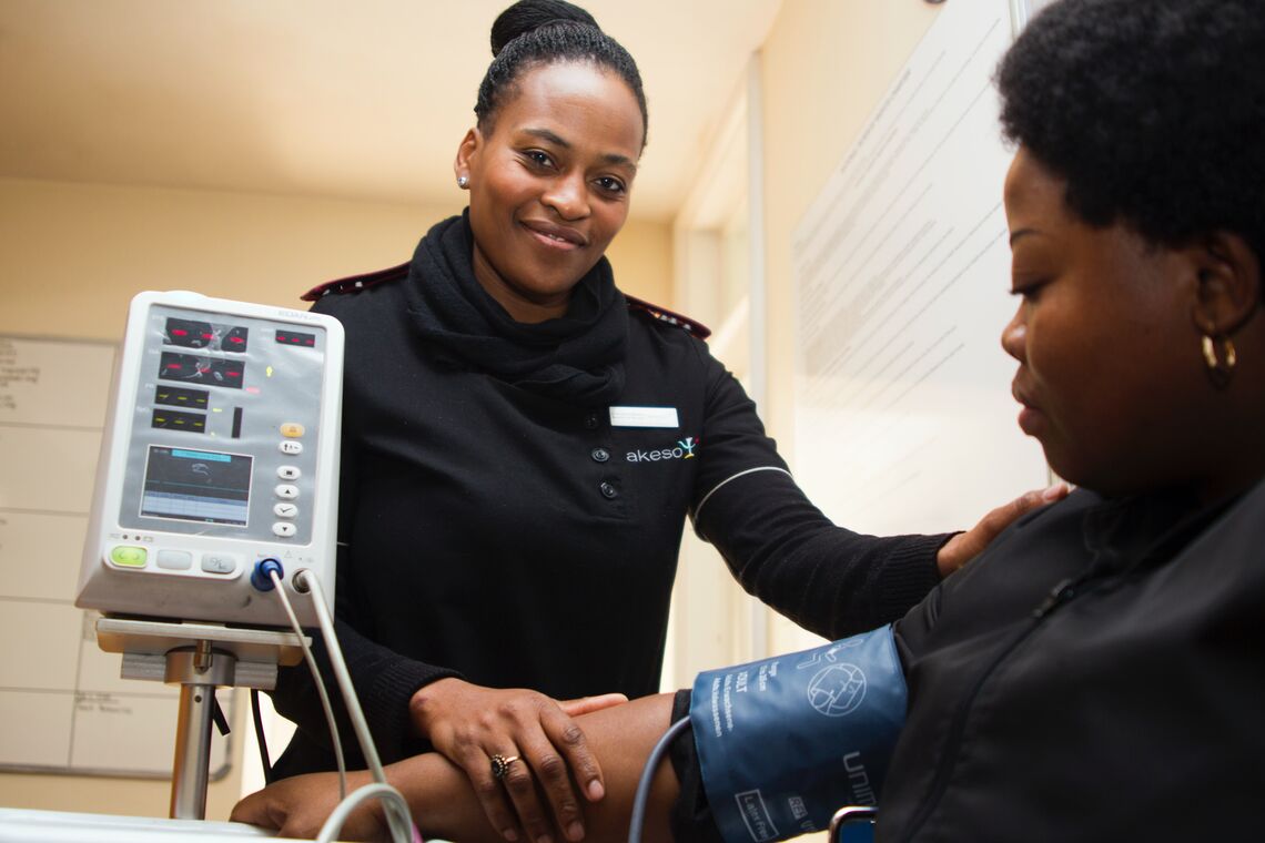 A healthcare worker checks a woman's blood pressure.