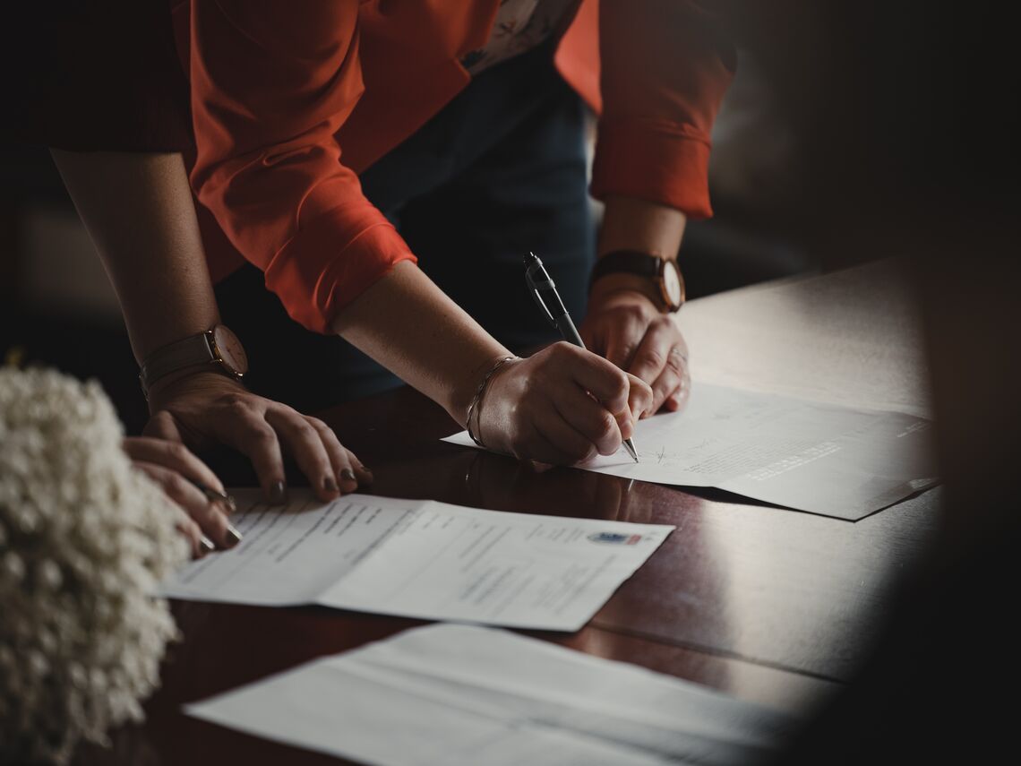 A woman signs a form on a table.