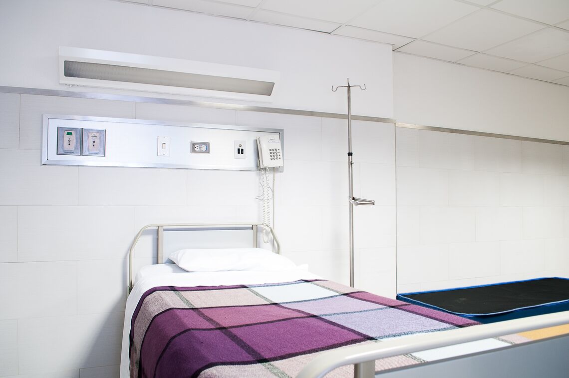 An empty hospital bed with a purple blanket