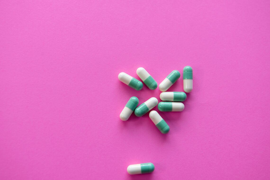 Half-white, half-teal capsules sit on a pink background