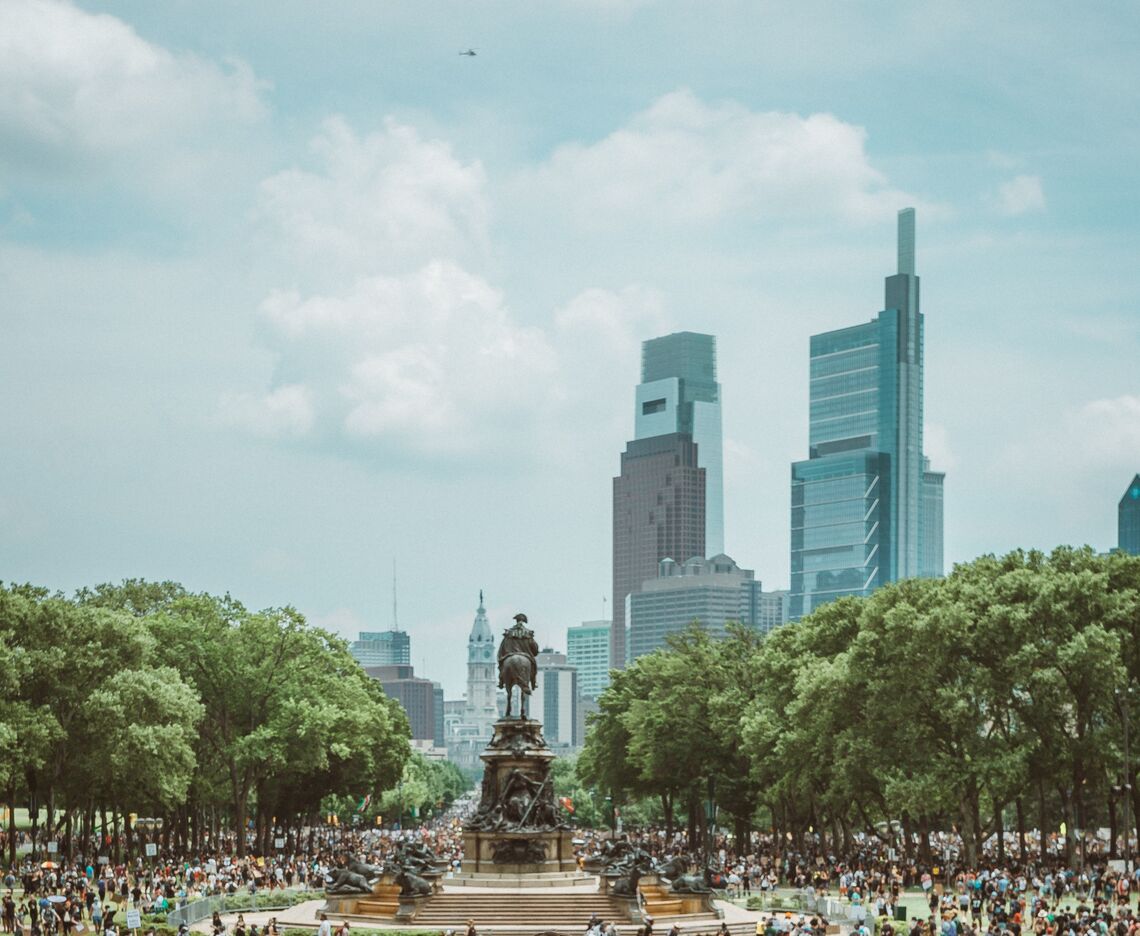 A crowd of people enjoy summer weather in downtown Philadelphia.