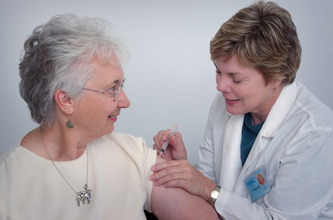 A healthcare provider gives an elderly woman a vaccine.