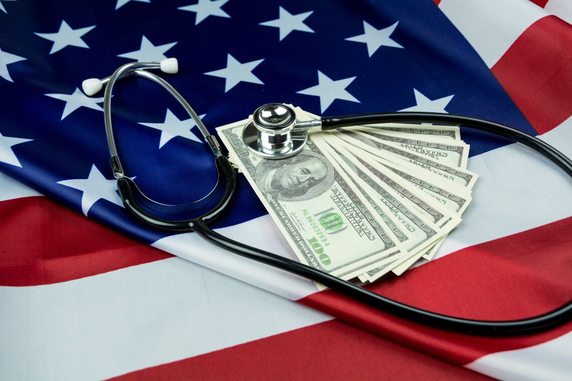 A stethoscope and dollar bills lie on an American flag