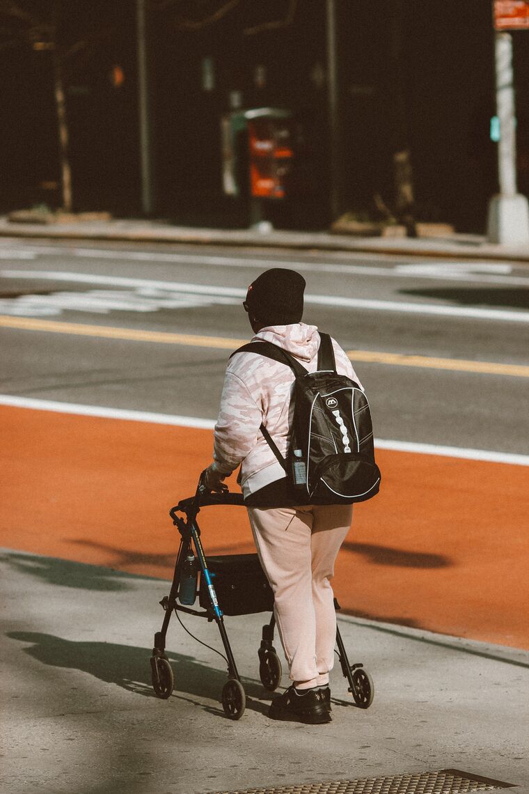 A person wearing a backpack and hat walks down the street.